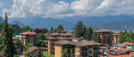 A residential area with multi-story buildings, some with balconies, surrounded by greenery and mountains in the background.