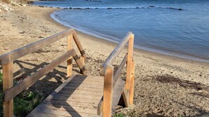 Una escalera de madera que lleva a una playa, con vista despejada al océano.