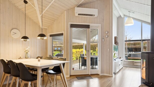 Una cocina moderna con paredes de madera, una amplia mesa de comedor y vistas al jardín a través de puertas de cristal.