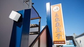 Ein Gebäude mit einem Schild in japanischer Schrift, einer blau-weißen Farbgestaltung und einer gut sichtbaren Telefonnummer.