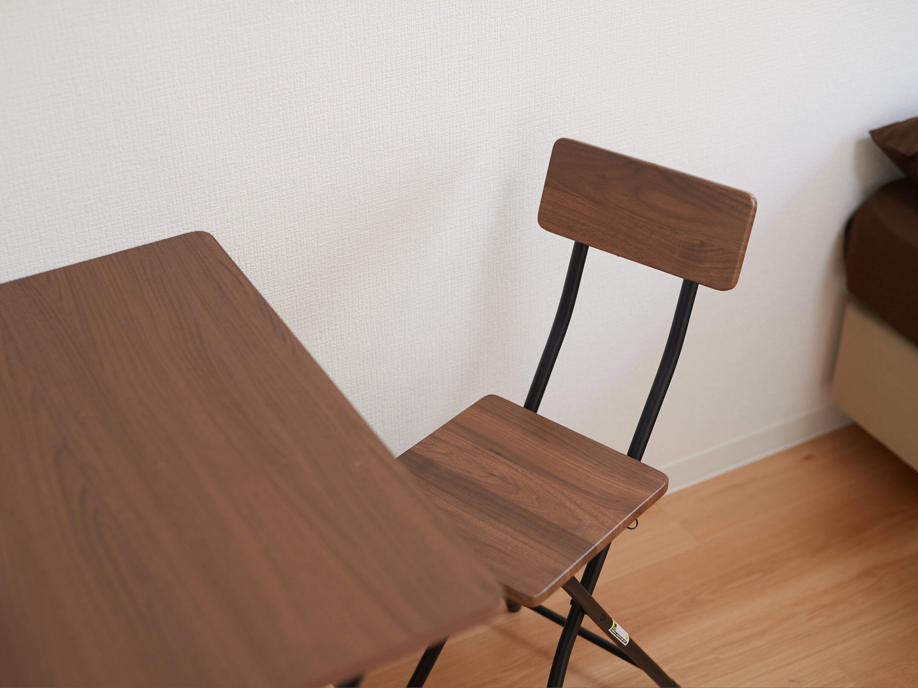 A wooden chair with a high backrest and a table with a wooden surface.