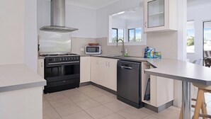 Una cucina moderna con piano cottura, microonde, lavastoviglie e una finestra che lascia entrare luce naturale.