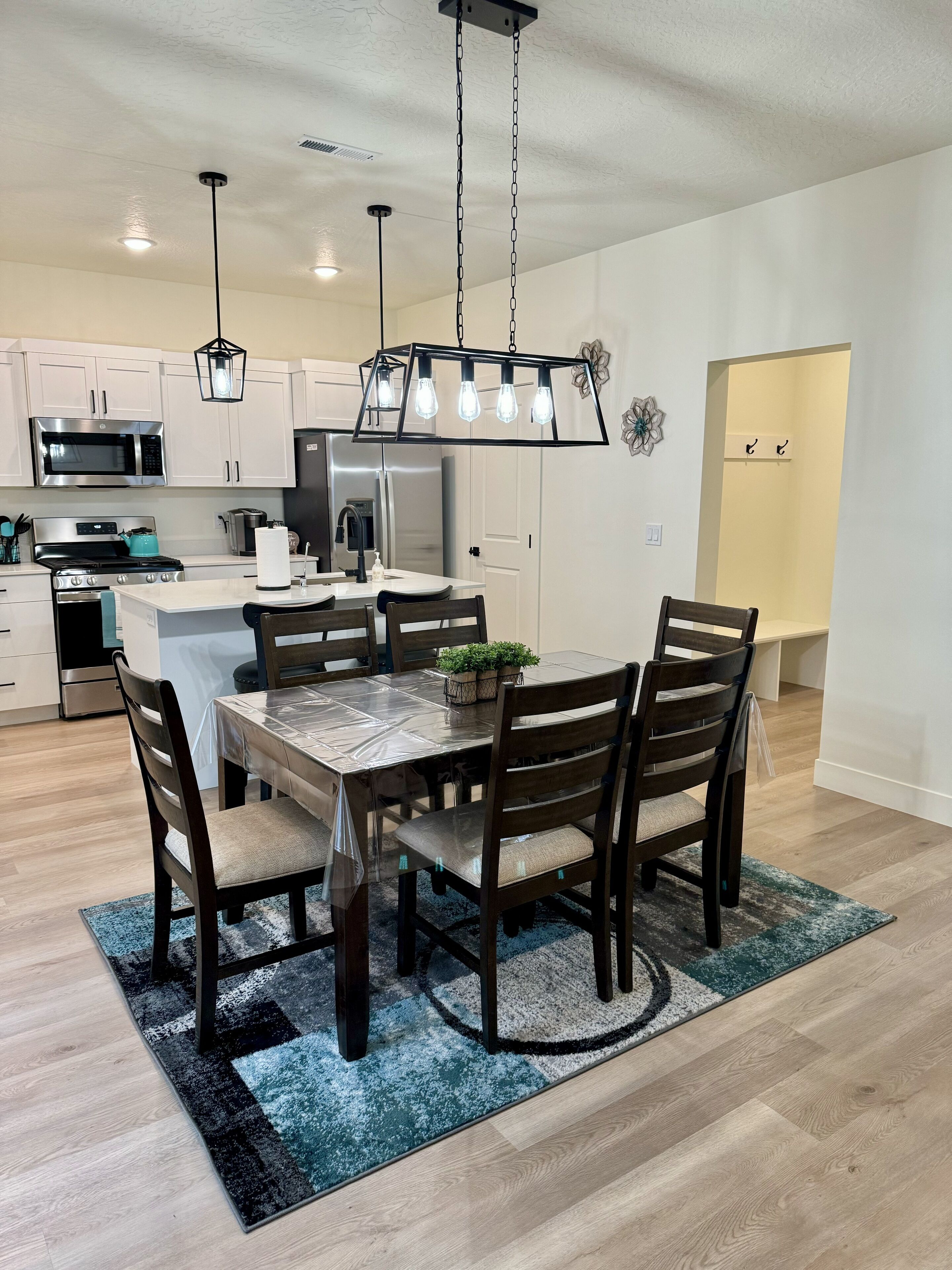 A modern kitchen with white cabinets, a stainless steel microwave, a gas stove, and a refrigerator.