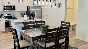 A modern kitchen with white cabinets, a stainless steel microwave, a gas stove, and a refrigerator.
