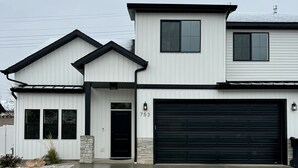 Une maison à deux étages avec un garage, un pilier en pierre et le numéro « 753 » inscrit sur le mur.