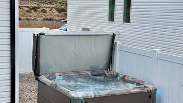 A hot tub with a marble exterior, positioned against a white house with a sloped roof.