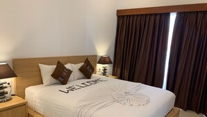 Una cama bien hecha con un letrero que dice 'WELCOME', cabecera de madera y dos almohadas decorativas.