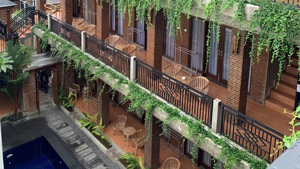 Un edificio de varios pisos con paredes de ladrillo, balcones con barandas negras y zonas de estar al aire libre.
