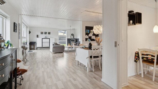 Een ruime woonkamer met een open haard, een eettafel en een keuken op de achtergrond.