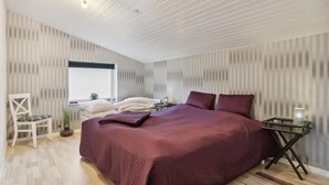 Een slaapkamer met een groot bed, een bureau en een stoel.