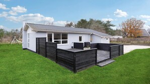 Eenlaags huis met een witte gevel en een zwarte houten schutting.