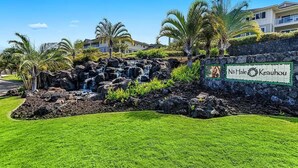 Placa de Na'alehu Keauhou, com uma cascata e palmeiras ao primeiro plano.