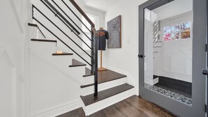 Eine Treppe mit dunklen Holzstufen und schwarzen Geländern, die zu einer Tür mit Glasfenster und einer teppichartigen Fußmatte führt.