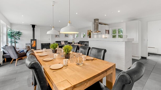 Uma sala de jantar moderna com mesa de madeira, cadeiras de couro preto e luminárias pendentes.