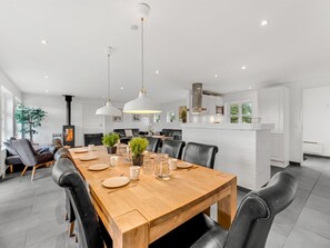 Een moderne eetruimte met een houten tafel, zwarte lederen stoelen en hanglampen.
