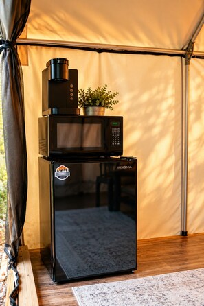 A black microwave oven with a digital display and a logo sticker on the front, placed on a wooden surface.
