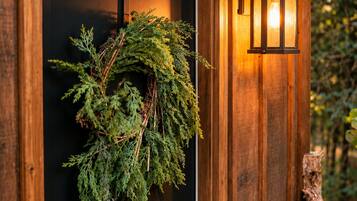Une porte en bois ornée d’une guirlande et d’une lanterne fixée au mur.