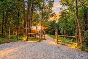A gravel path leading to a rustic wooden structure surrounded by trees.