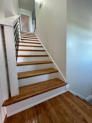 Una escalera con escalones de madera y paredes blancas.