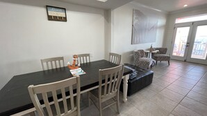 Un comedor con una mesa larga, cuatro sillas, un ancla decorativa y un letrero en la pared.