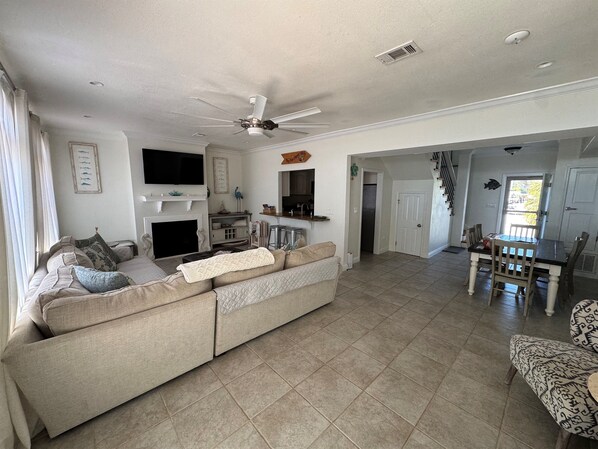 A living room with a beige sofa, a flat-screen TV, and a ceiling fan.