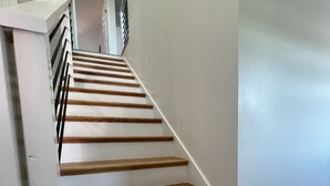Una escalera con escalones de madera y paredes blancas.