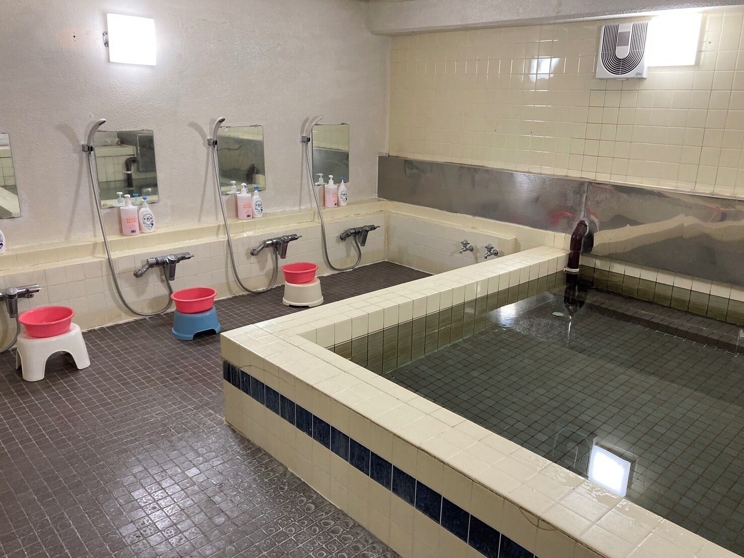 A public bathroom with multiple sinks, mirrors, and a large bathtub.