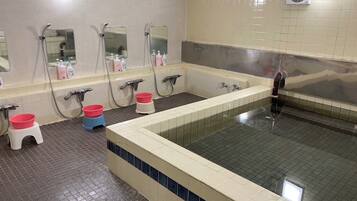 A public bathroom with multiple sinks, mirrors, and a large bathtub.
