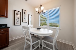 Enjoy meals in this elegant dining area with a round table and four chairs, a chandelier, and framed artworks on the walls.