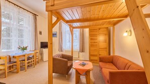 Una habitación acogedora con techo de madera, un sofá, una mesita y un televisor.