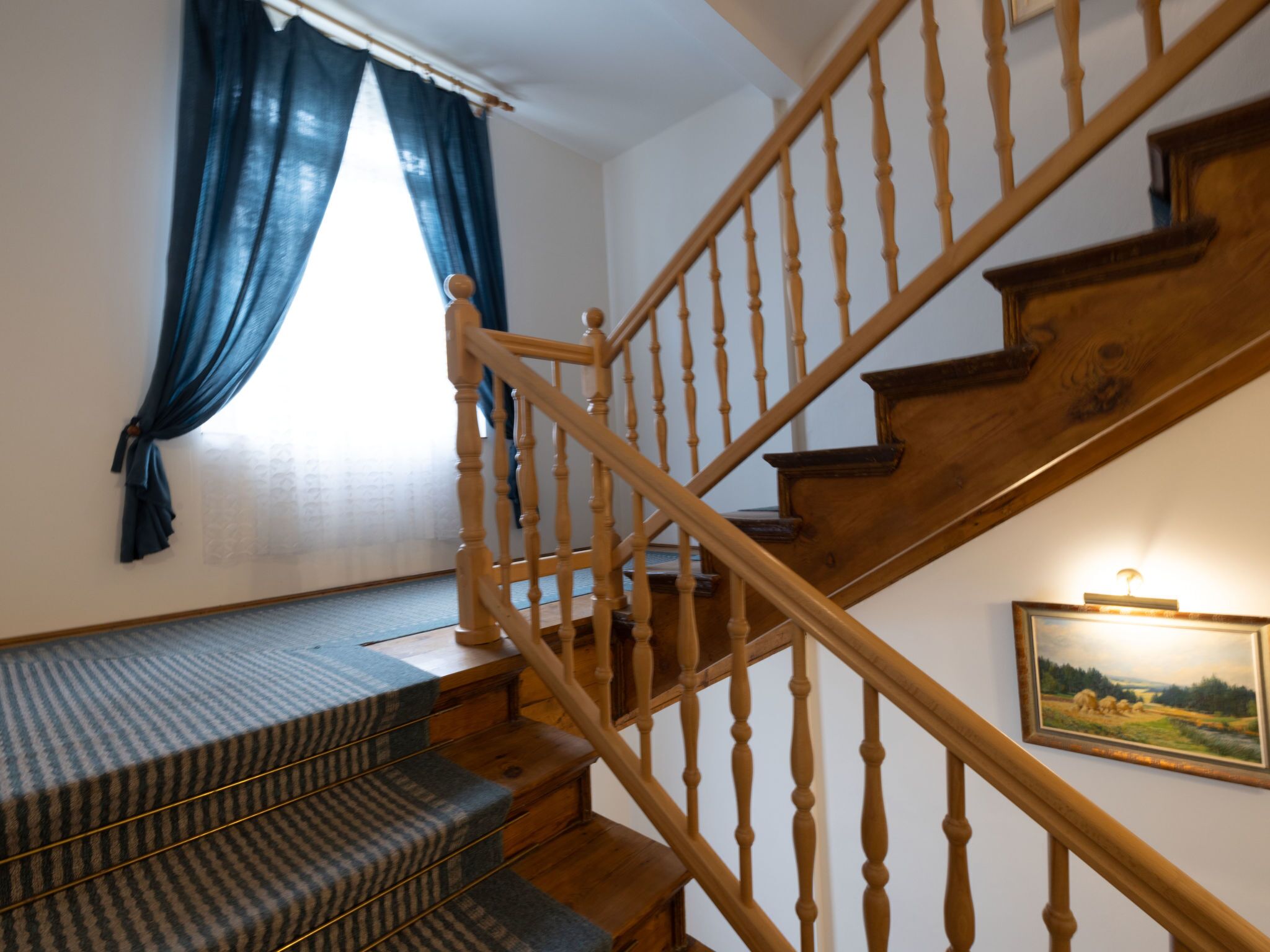Una escalera con barandillas de madera y peldaños alfombrados.