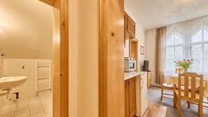 A compact kitchen with a microwave, a small refrigerator, and a dining area with a table and chairs. - Stříbrný pramen by Interhome (Janské Lázně)