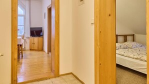 Un pasillo que lleva a un dormitorio con una cama y televisión en la habitación contigua.