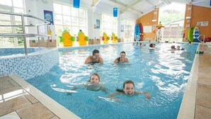 Una piscina interior con agua cristalina, un trampolín y juguetes de colores.