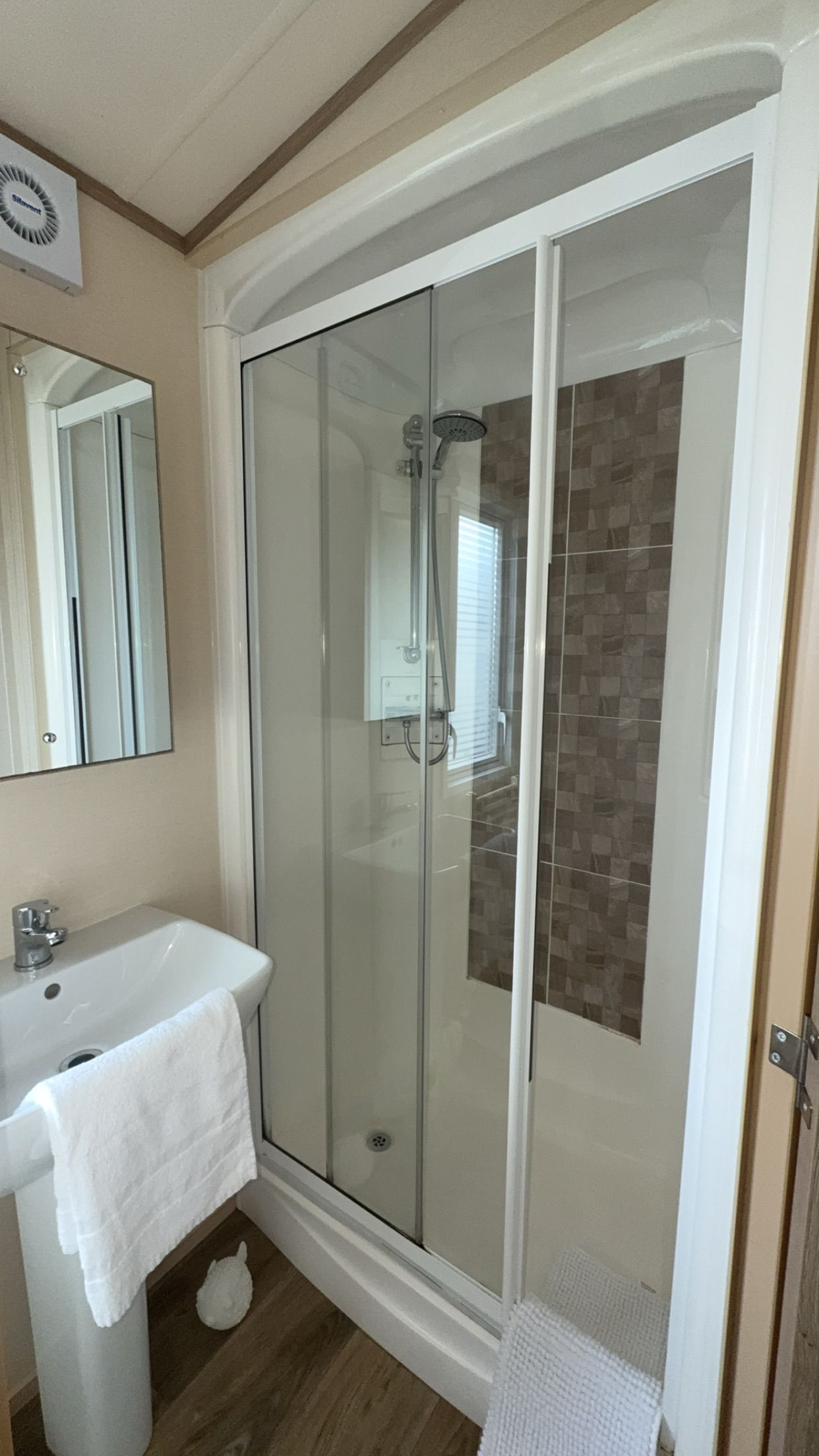 Une salle de bain avec une douche à parois de verre, un lavabo blanc et un miroir.