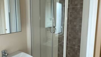 Une salle de bain avec une douche à parois de verre, un lavabo blanc et un miroir.