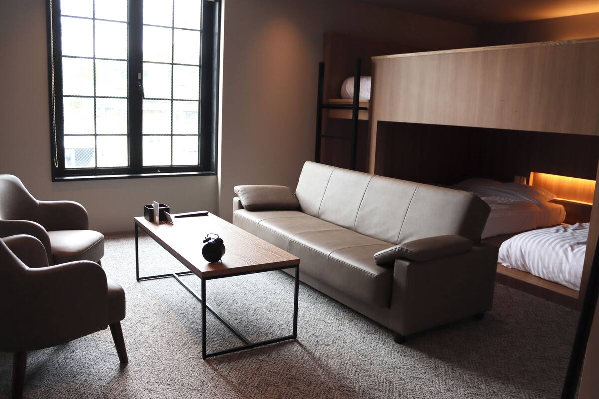 Una habitación moderna y compacta con sofá, una mesita y una cama litera.