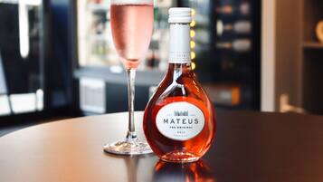 A bottle of Mateus wine and a glass of rosé wine on a table.