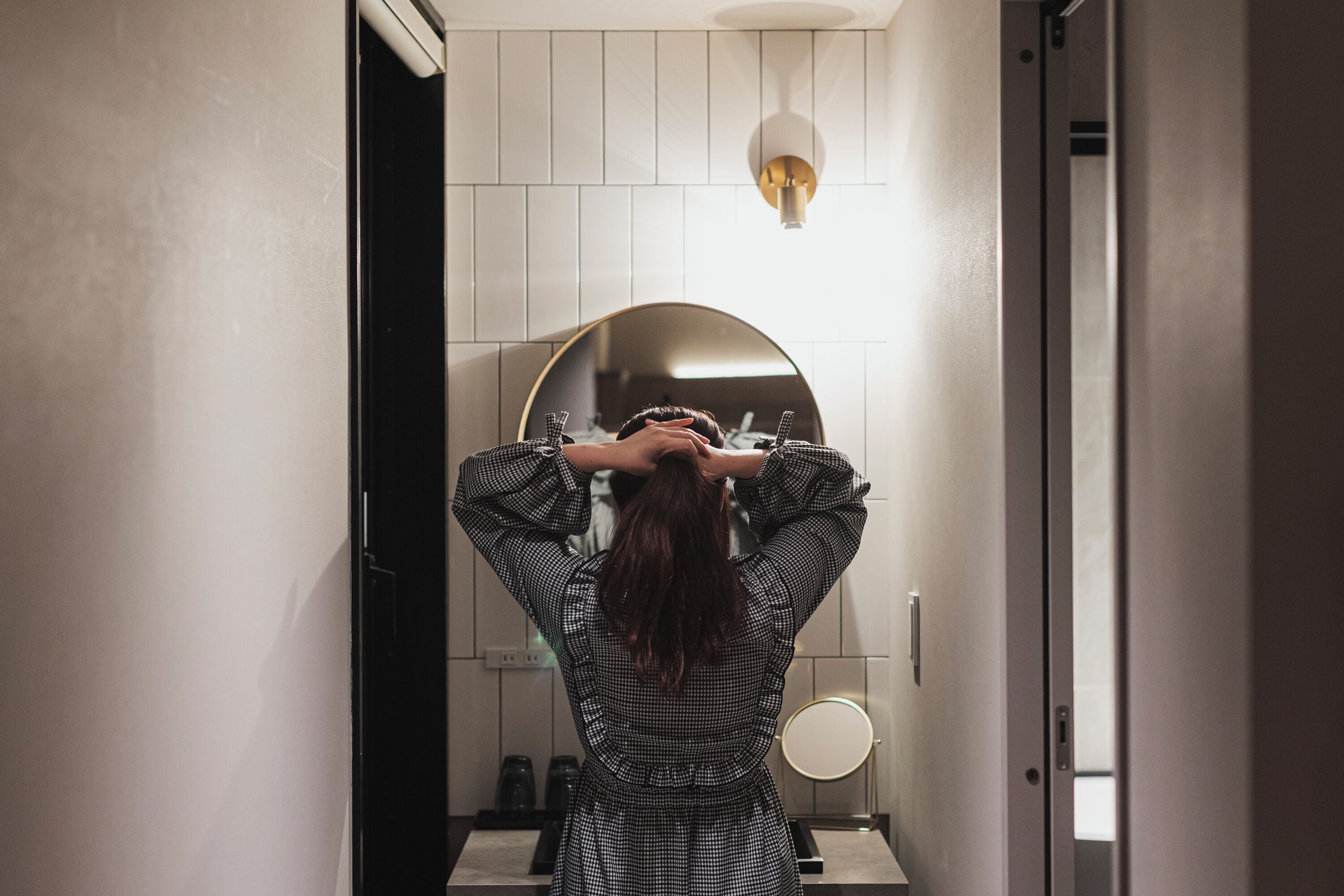 A bathroom with a large mirror, a round mirror, and a light fixture above the mirror.