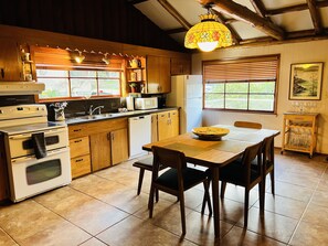 A kitchen with wooden cabinets, a dining table with chairs, a microwave, and a refrigerator.