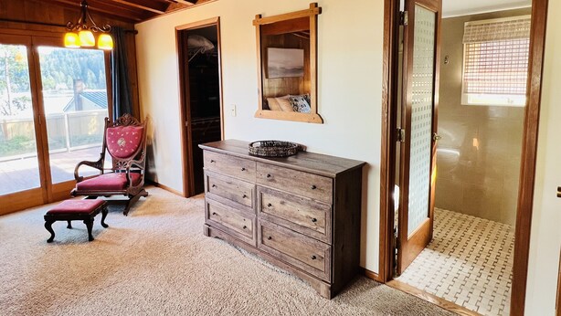 Een kamer met een houten plafond, een houten dressoir, een spiegel en een stoel.