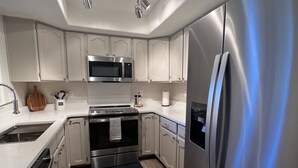 Una cucina moderna con elettrodomestici in acciaio inox, mobili bianchi e un'isola centrale.