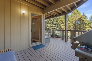 Une terrasse couverte avec un barbecue, une porte moustiquaire et une vue sur les arbres.