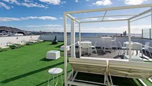A rooftop terrace with a clear view of the sea and a distant town.