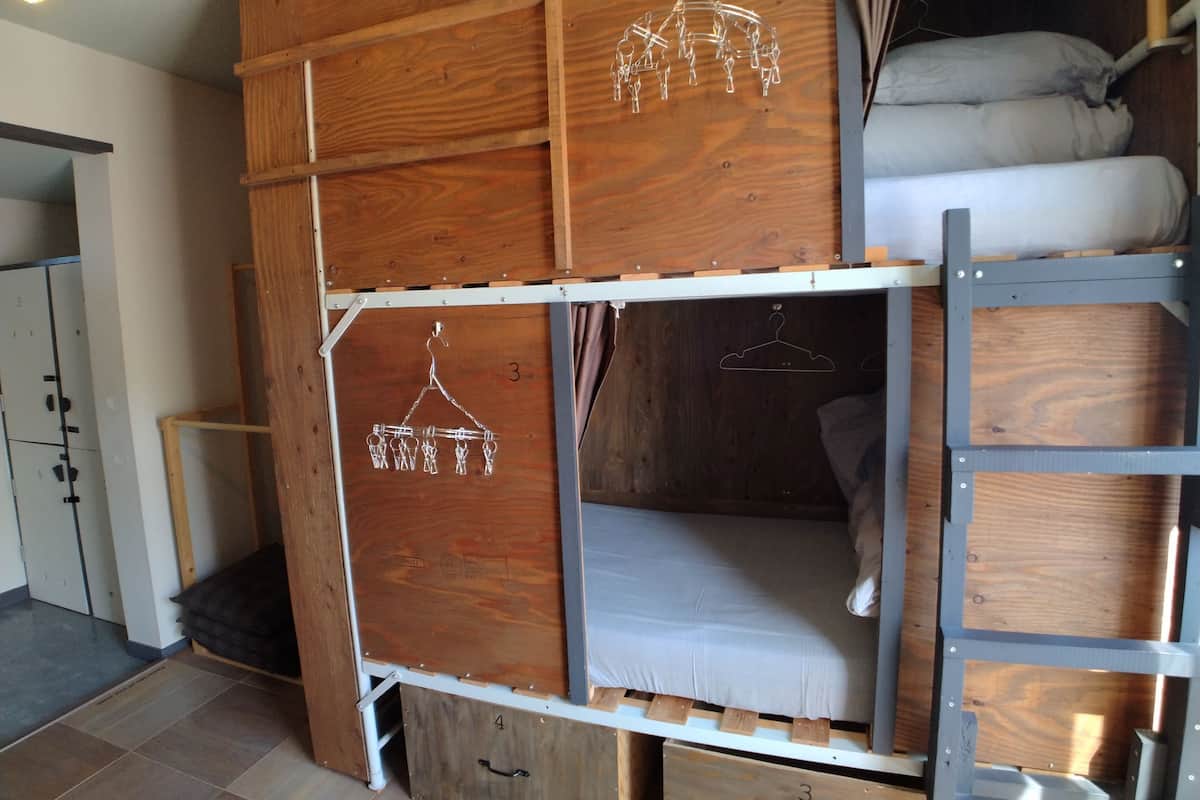 A bunk bed with wooden panels and metal railings, a hanging light fixture, and a small wardrobe with a handle.