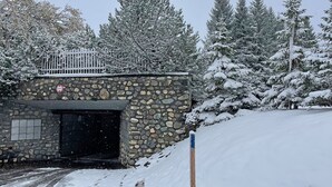 Kivinen rakennus, jossa on metallinen portti, ja sen ympärillä on lumipeitteisiä puita.