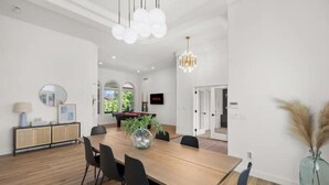 Zona pranzo moderna con tavolo in legno, sedie nere e lampadario.