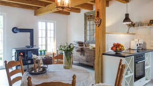 Een gezellige keuken met een houtkachel, een eettafel met stoelen en een fruitschaal op het aanrecht.