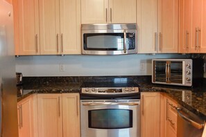 A kitchen with stainless steel appliances, wooden cabinets, and granite countertops.