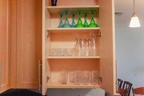 Een houten kast met planken vol met verschillende glazen.